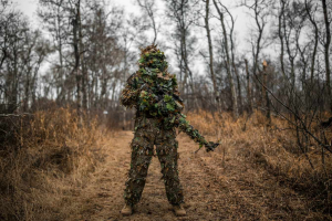 person standing in ghillie suit in woods