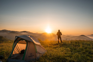 person standing near tent at sunset