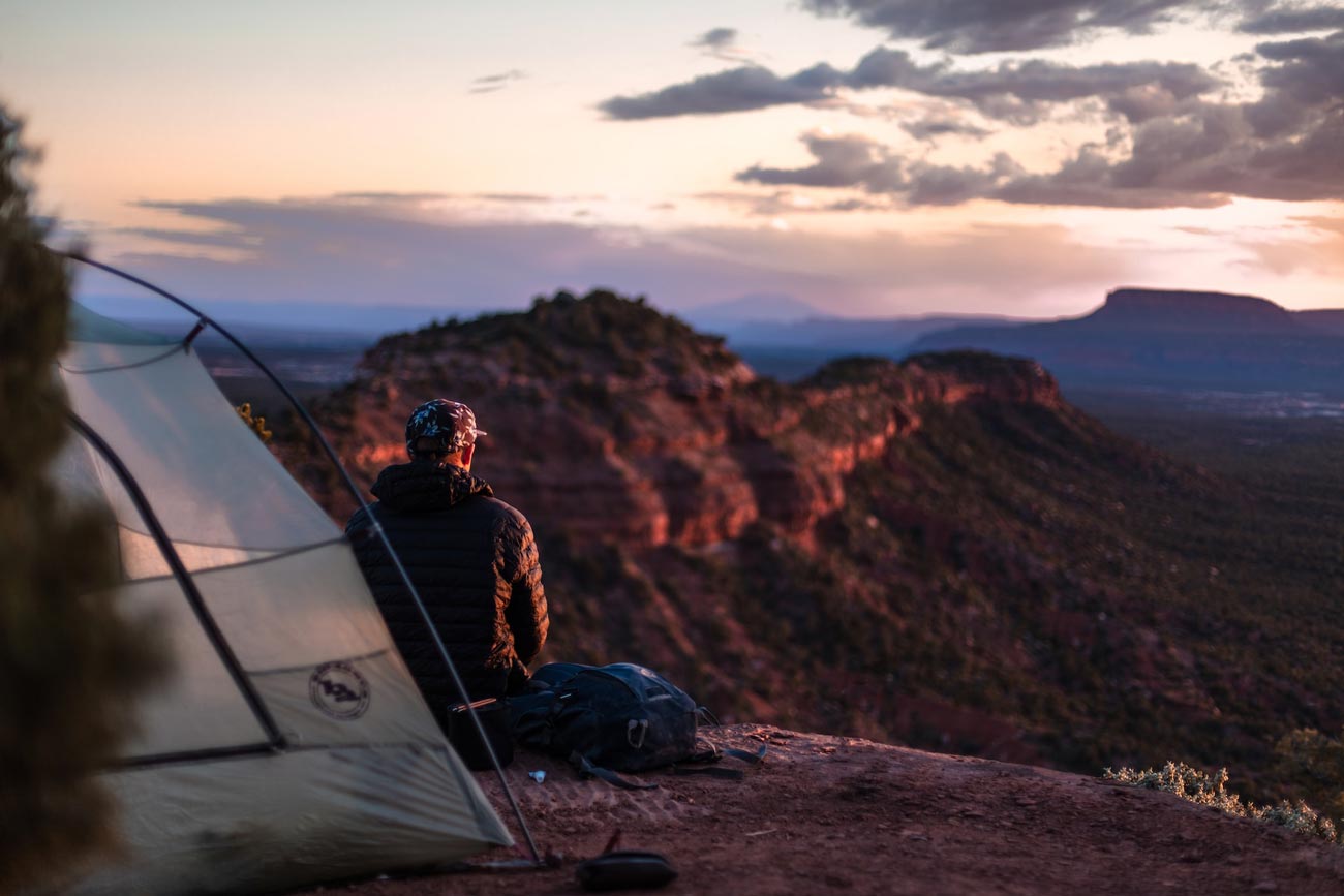 man looking at horizon by camping tent