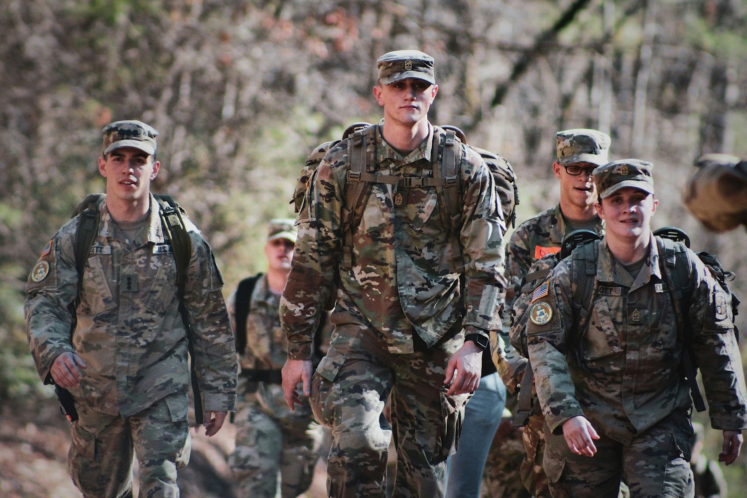 men in camouflage military uniform walking through a field